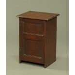 A mahogany bedside cabinet, with chamfered edge above a panelled door opening to shelves.