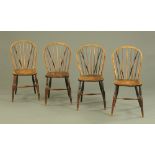 A set of four Windsor dining chairs, each with solid seat, turned legs and stretchers.