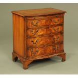 A mahogany reproduction serpentine fronted crossbanded chest of drawers with slide and raised on