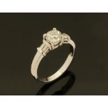 An 18 ct white gold ring, set with a central diamond with baguettes to shoulders,