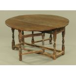 An antique oak gate legged dining table, with demi lune drop flaps,