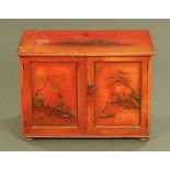 A chinoiserie stained and painted two door cabinet, decorated with figures, branches and fence.