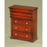 A Victorian miniature Scotch chest of drawers, with glass knob handles and raised on a plinth base.