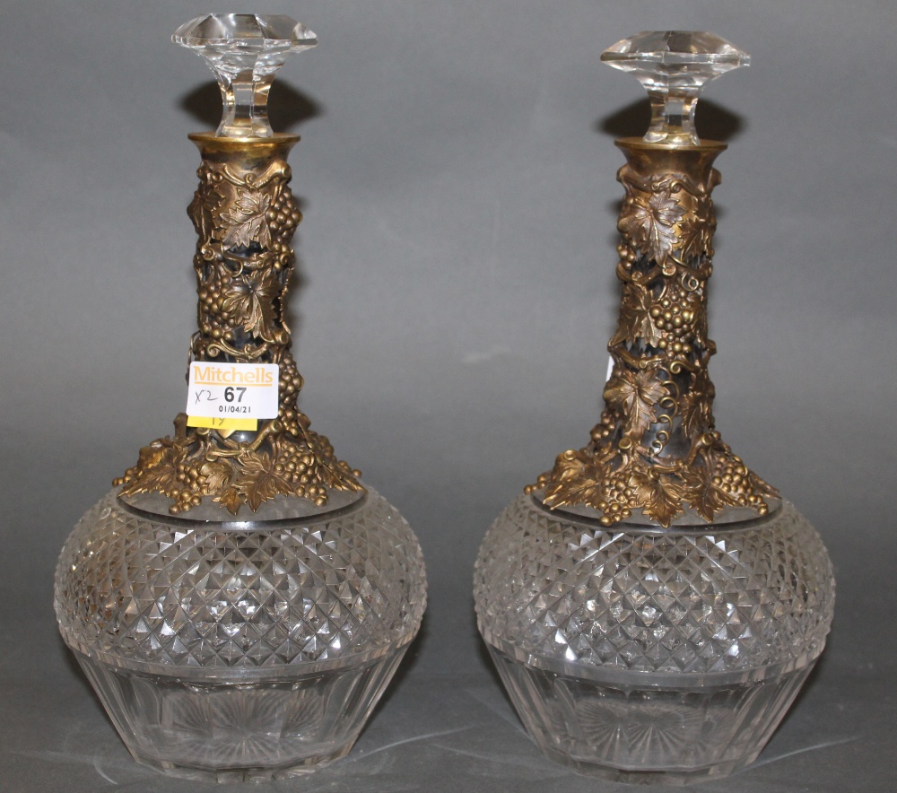 A pair of gilded white metal and cut glass bottle shaped decanters and stoppers,