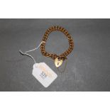 A gold plated flat link bracelet with heart shaped padlock clasp