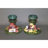 A pair of Moorcroft pottery Pansy pattern squat candlesticks on a green ground, 8 cm high.