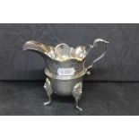 An Elizabeth II silver cream jug of George II design with pronounced spout, engraved with leaves,