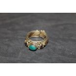 A Tri-coloured metal ring of Indian design, set to centre with oval green hard stone,