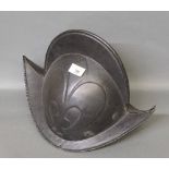 A reproduction black painted and embossed metal helmet of 16th century Spanish design, 26 cm high.