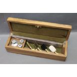 A wooden cased shotgun cleaning set, complete with oil bottle, 12 bore snap caps etc.