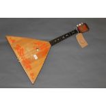 A 20th century Balalaika, the body painted in red with scrolled leaves, 67 cm long,