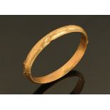 A 9 ct gold stiff bracelet, engraved with leaf scrolls. Weight 7 grams.