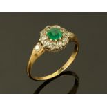 A gold coloured emerald and diamond cluster ring, with diamond set shoulders. Size S.
