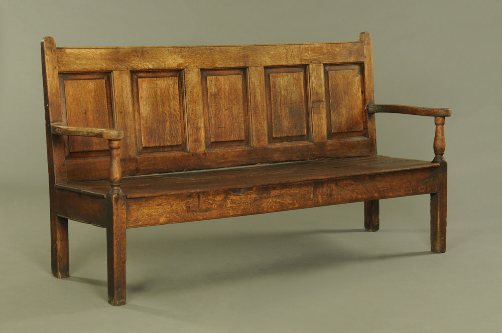 An 18th century oak five panelled settle, with outswept arms,