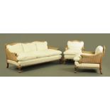 A walnut framed bergere lounge suite, comprising two chairs and settee,