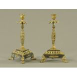 A pair of Regency brass candlesticks, with triform bases and raised on three paw feet.