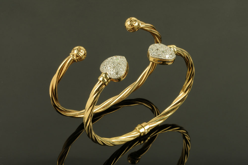 Two 9 ct gold bangles, one with heart shaped terminals set with paste stones, 25.2 grams gross.