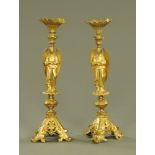 A pair of brass pricket candlesticks, with winged angel supports and raised on three scroll feet.