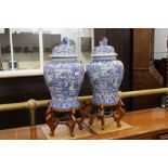 A pair of blue and white Chinese vases with lids on stands,