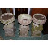 Three reconstituted stone garden planters raised on plinths,