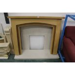 A modern light oak fire surround with marble hearth and back