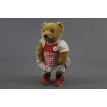 A Lakeland Bears teddy bear, wearing a corduroy and checkered patterned dress,