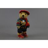 A Lakeland Bears teddy bear, wearing a red corduroy cap, knitted jumper,
