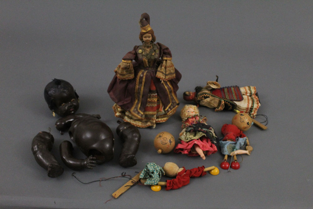 A group of dolls, parts, and puppets of varying ages and designs,