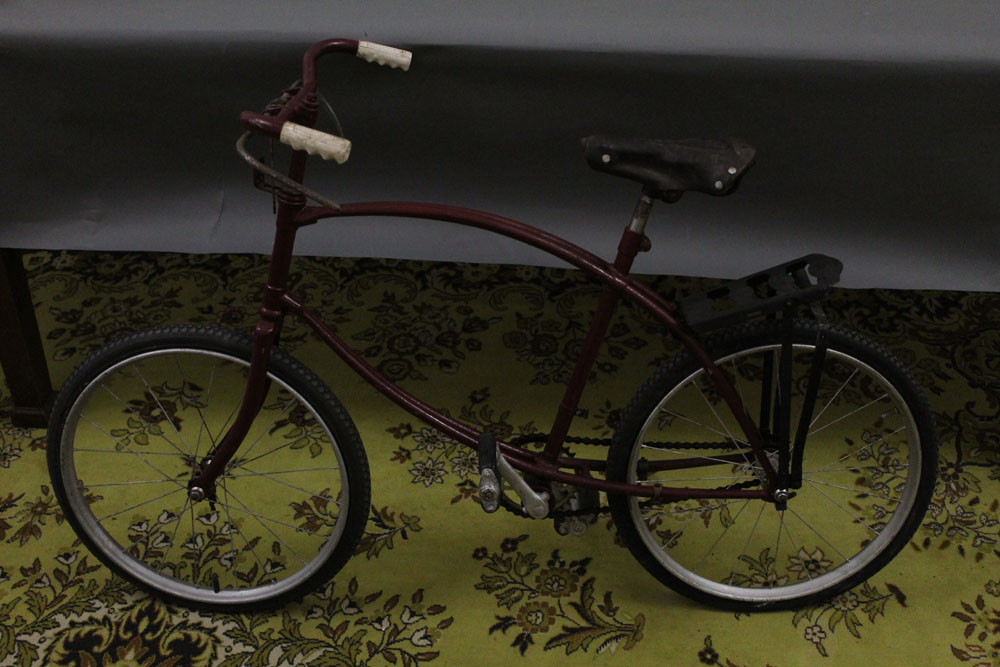 A mid 20th century bicycle, overpainted in maroon, having a bowed frame,