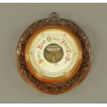 An early 20th century circular carved oak barometer, with aneroid movement. Diameter 31 cm.