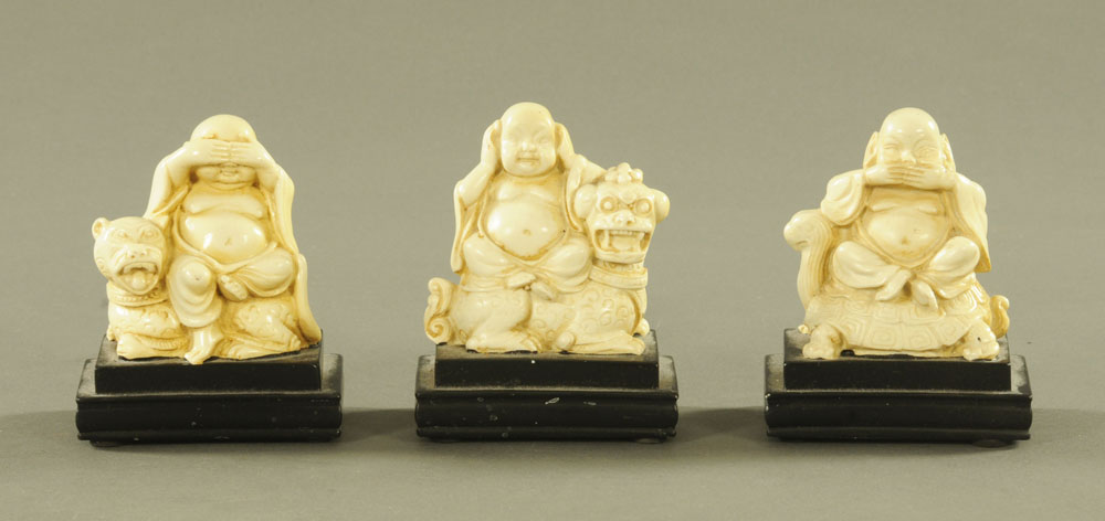 Three Chinese cream and black resin figures of Buddha. 10 cm high.