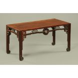 An antique Chinese hardwood low table, with pierced frieze and moulded legs with scroll feet.