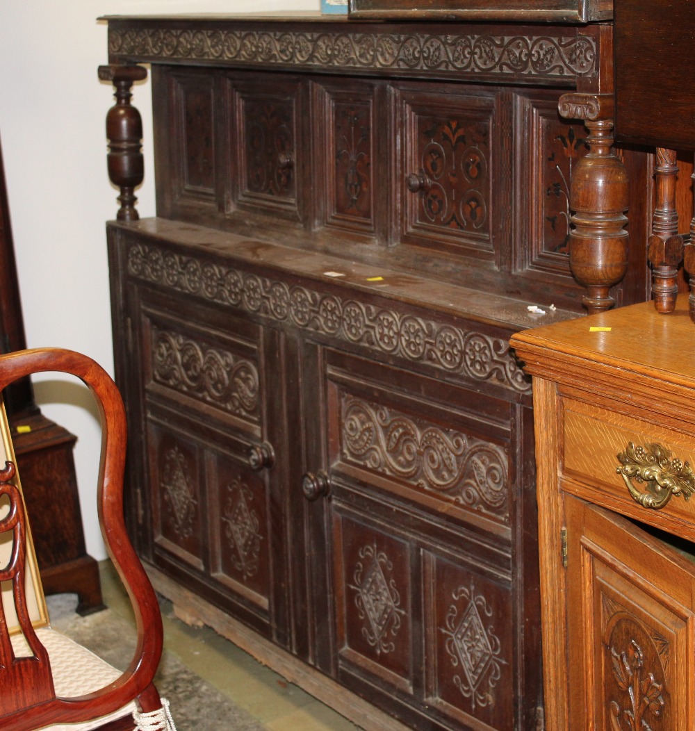 An oak carved court cupboard with inlaid doors and carved panels measuring 135 cm tall x 160 wide