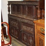 An oak carved court cupboard with inlaid doors and carved panels measuring 135 cm tall x 160 wide