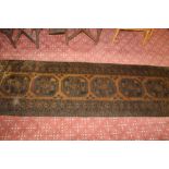 An eastern fringed patterned runner woven in blue and brown and having repeating geometric designs