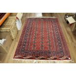 A Turkoman style rug, woven in red, blue, and cream, with repeating geometrical designs,