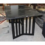 A black ash dining table raised on angled legs and with an extra leaf