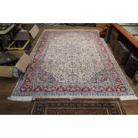 A large eastern fringed patterned rug woven in blue and pink with central floral medallion and