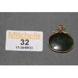 A gilt metal mounted jade oval pendant engraved to front with native figure and to reverse worded