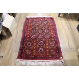 An eastern fringed patterned rug, woven in red, blue, and cream, with repeating geometrical designs,