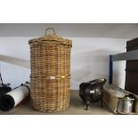 A lidded cylindrical wicker linen basket