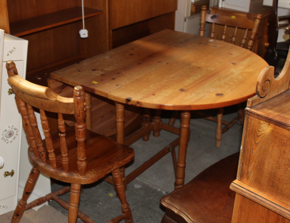 A pine drop leaf and gate leg table together with two pine spindle back dining chairs