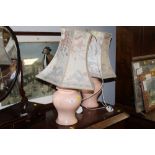 A pair of pink coloured table lamps with floral patterned shades