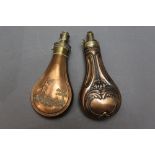 * Two copper bodied powder flasks, the first with shotgun and dog decoration 18 cm,