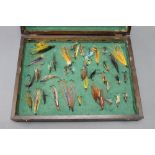 An oak box with green baize lined interior, filled with vintage salmon flies.