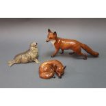 Three Beswick figures, standing fox, lying fox, and a seal, model No. 1534.