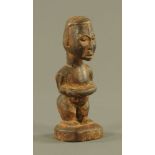 An African carved and stained wood figure of a man holding a basket, 18 cm high.