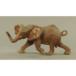 A tropical carved hardwood model of an African elephant, shown standing in striding motion.