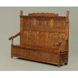 A Victorian carved oak settle, decorated with floral, armorial and religious panels,