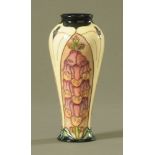 A Walter Moorcroft tube lined pottery "Foxglove" pattern baluster vase, 21 cm high,